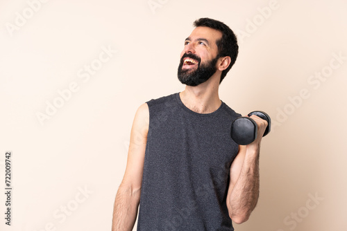 Caucasian sport man with beard making weightlifting over isolated background happy and smiling