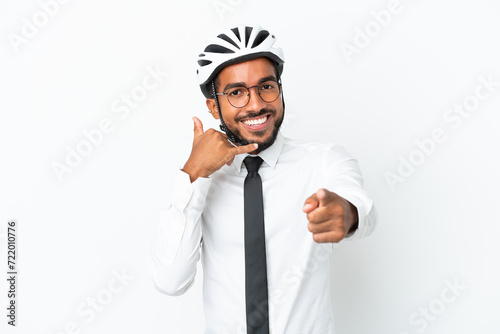 Young business latin man holding a bike helmet isolated on white background making phone gesture and pointing front