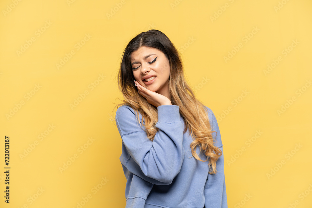 Young Russian girl isolated on yellow background with toothache