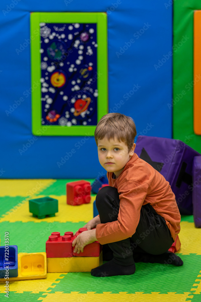 A cute boy is playing with large plastic toy blocks on a soft floors in the playroom. A cute boy is playing with large plastic toy blocks on a soft floors in the playroom.