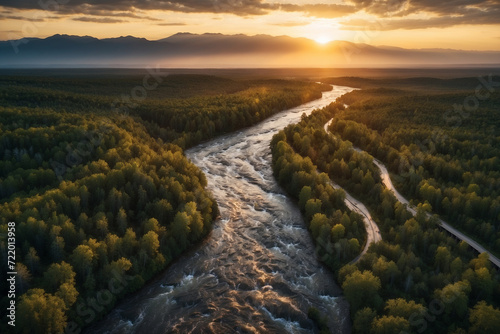 Elongated river flow winding in the middle of the forest at sunset seen from a high drone viewpoint