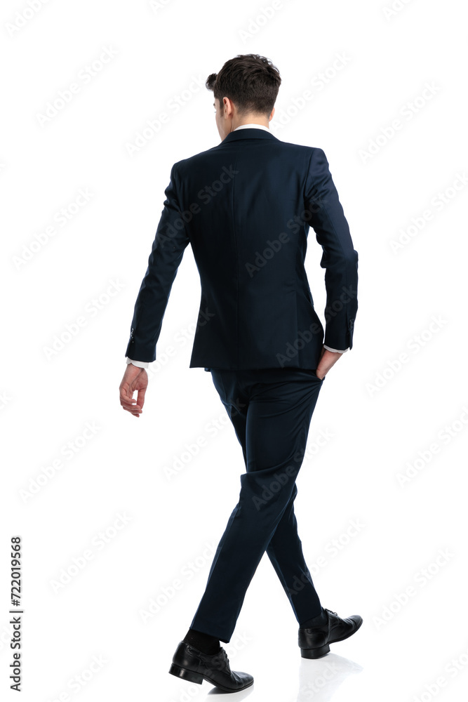 elegant businessman looking to side and walking with hand in pocket elegant businessman looking to side and walking with hand in pocket