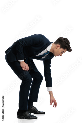 elegant fashion man bending over and taking something from the floor