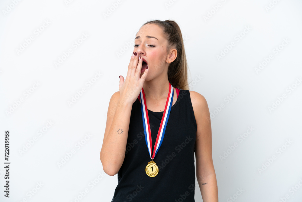 Young caucasian woman with medals isolated on white background yawning and covering wide open mouth with hand Young caucasian woman with medals isolated on white background yawning and covering wide open mouth with hand