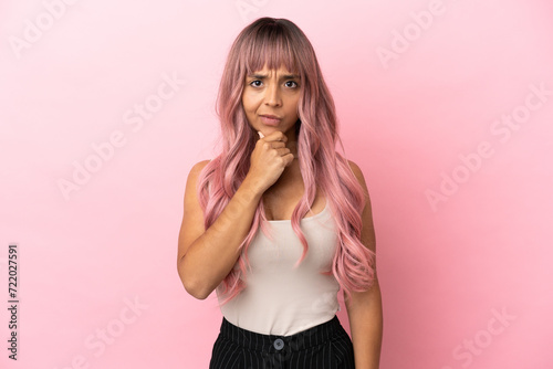 Young mixed race woman with pink hair isolated on pink background thinking