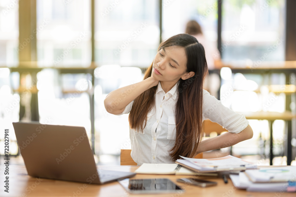 A female employee stretching lazy at the desk to relax while working in the office. Feeling stressed and achy from work. A female employee stretching lazy at the desk to relax while working in the office. Feeling stressed and achy from work.