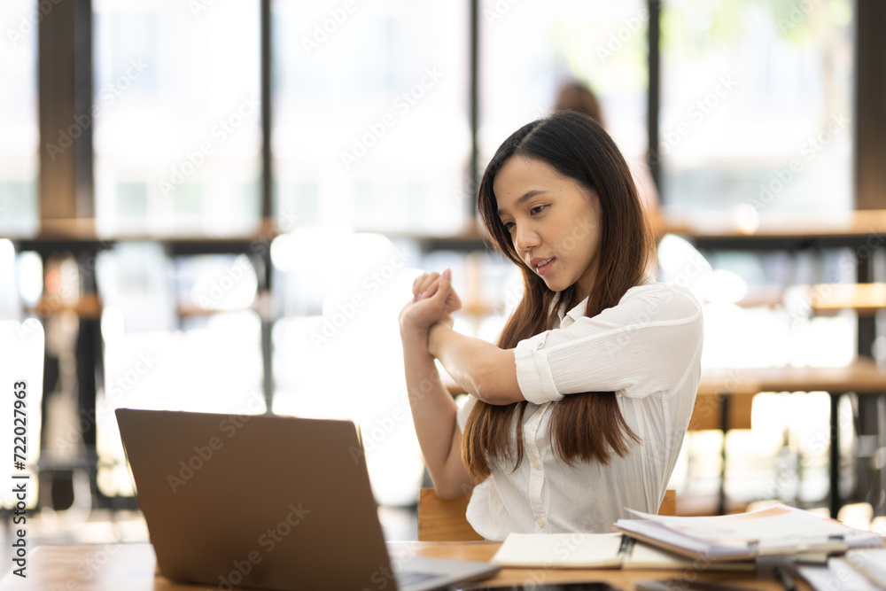 A female employee stretching lazy at the desk to relax while working in the office. Feeling stressed and achy from work. A female employee stretching lazy at the desk to relax while working in the office. Feeling stressed and achy from work.