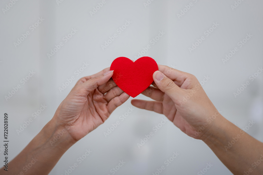Close-up of hands holding a red heart-shaped Valentine's Day gifts, February 14, symbol of love. Close-up of hands holding a red heart-shaped Valentine's Day gifts, February 14, symbol of love.