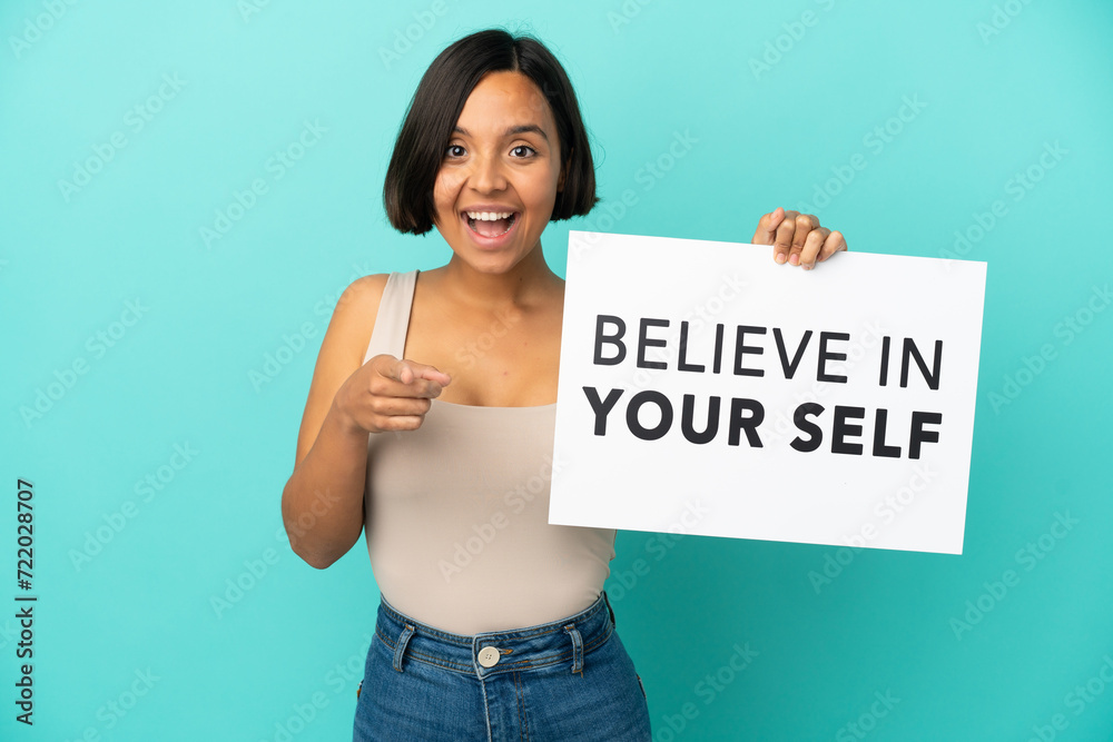 Young mixed race woman isolated on blue background holding We Want You board and pointing to the front Young mixed race woman isolated on blue background holding We Want You board and pointing to the front