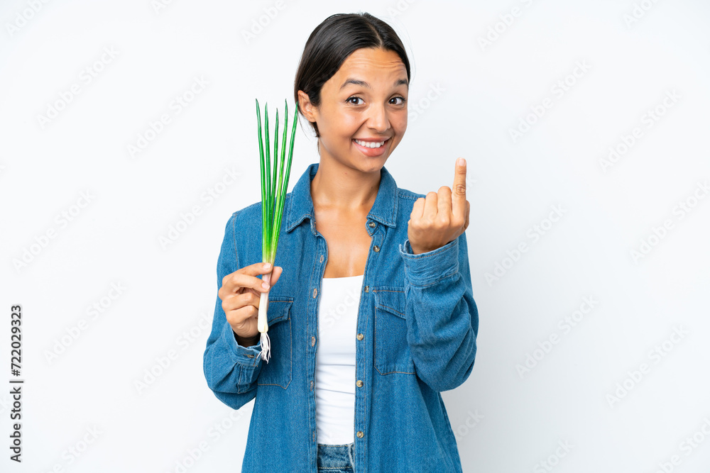Young hispanic woman holding chive isolated on white background doing coming gesture Young hispanic woman holding chive isolated on white background doing coming gesture