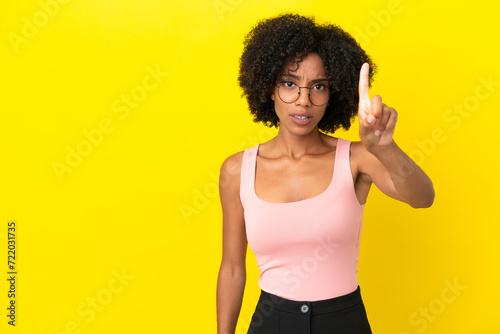 Young African American woman isolated on yellow background counting one with serious expression