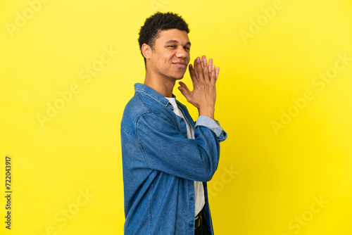 Young African American man isolated on yellow background scheming something