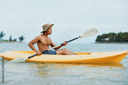 Happy Asian Man Kayaking on a Tropical Beach, Enjoying Summer Vacation