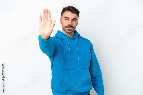 Young caucasian man isolated on white background making stop gesture