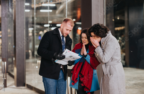 Wallpaper Mural Three business professionals engaged in a serious discussion over paperwork outside a modern office building at night. Torontodigital.ca