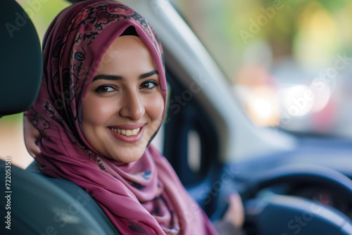 Smiling muslim woman behind steering wheel drives car