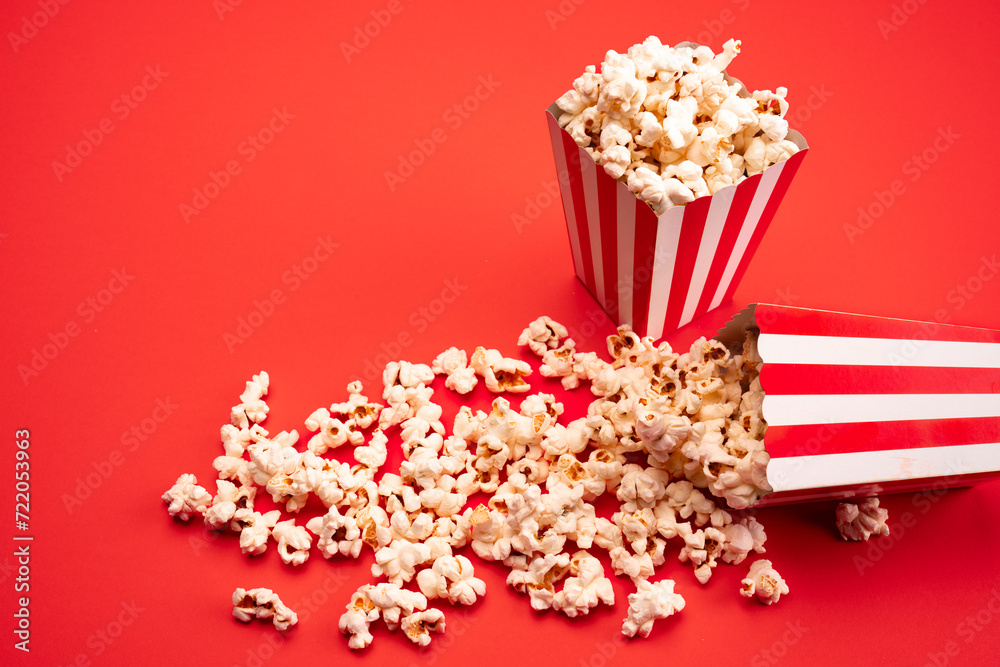 Popcorn in red and white striped paper box isolated on red background Popcorn in red and white striped paper box isolated on red background