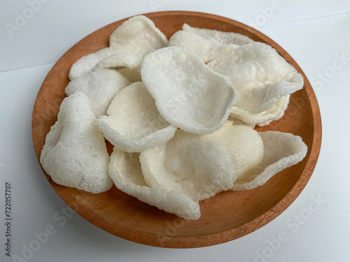 Kerupuk bawang putih, crackers made from tapioca flour and garlic, on wooden plated, isolated on white background photo