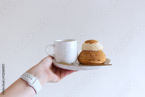 Tasty coffee and craquelin choux pastry cream-puff dessert filled with cream on a plate.