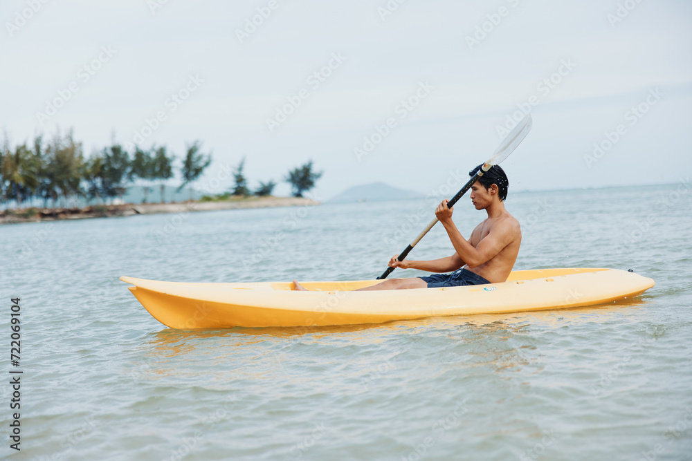 Happy Asian Man Enjoying Kayaking Adventure on a Tropical Beach