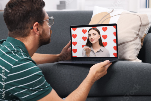 Long distance love. Man having video chat with his girlfriend via laptop at home