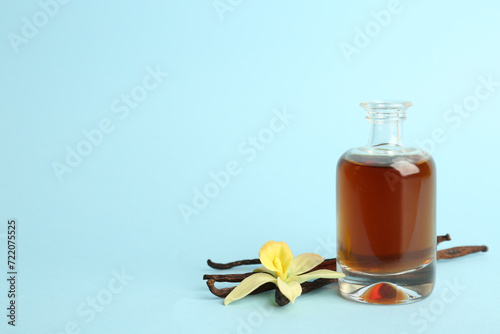 Aromatic homemade vanilla extract on light blue background. Space for text