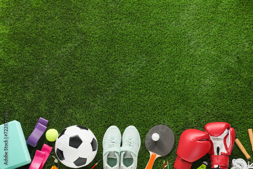 Different sport equipment and sneakers on green grass, flat lay. Space for text