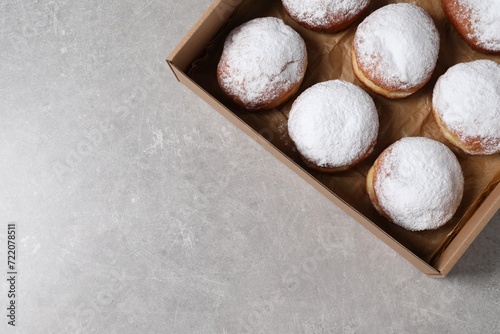 Delicious buns with powdered sugar in box on light grey table, top view. Space for text photo