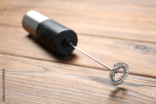 Black milk frother wand on wooden table, closeup