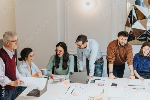 Canvas Print A multigenerational group of men and women gather around a table, collaborating in a business meeting focused on strategy and innovation