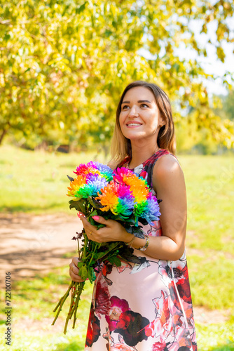 a beautiful slender girl in a bright elegant dress with a bouquet of flowers walks in a summer park.