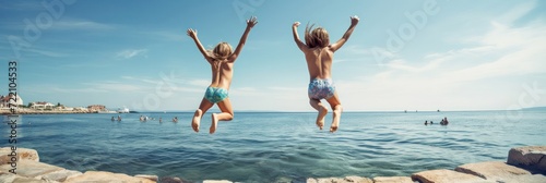 Two boys jump into the sea from a pier mid air portrait. Travel and vacation concept. Travel to warm countries. Family vacation. place for text banner photo