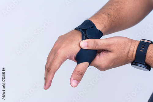 A man massages the first metacarpal joint. Wearing an ultra-thin compression wrist and thumb brace for texting thumb syndrome, carpal tunnel or tendonitis. photo
