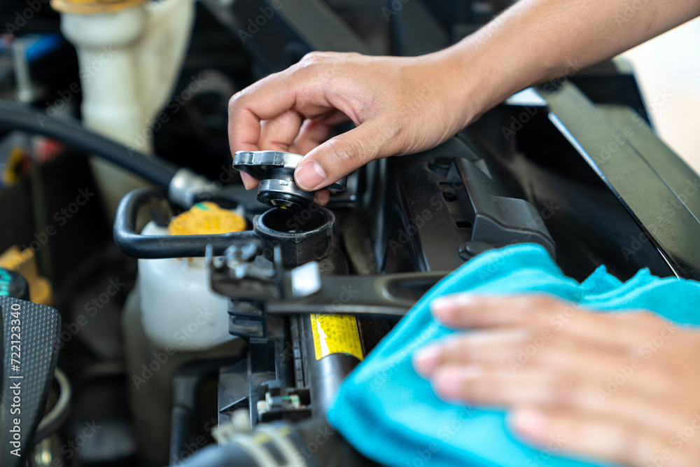 A woman is opening the car's radiator cap