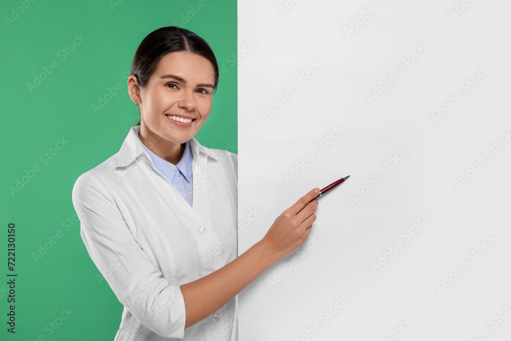 Ophthalmologist pointing at blank banner on green background, space for text Ophthalmologist pointing at blank banner on green background, space for text