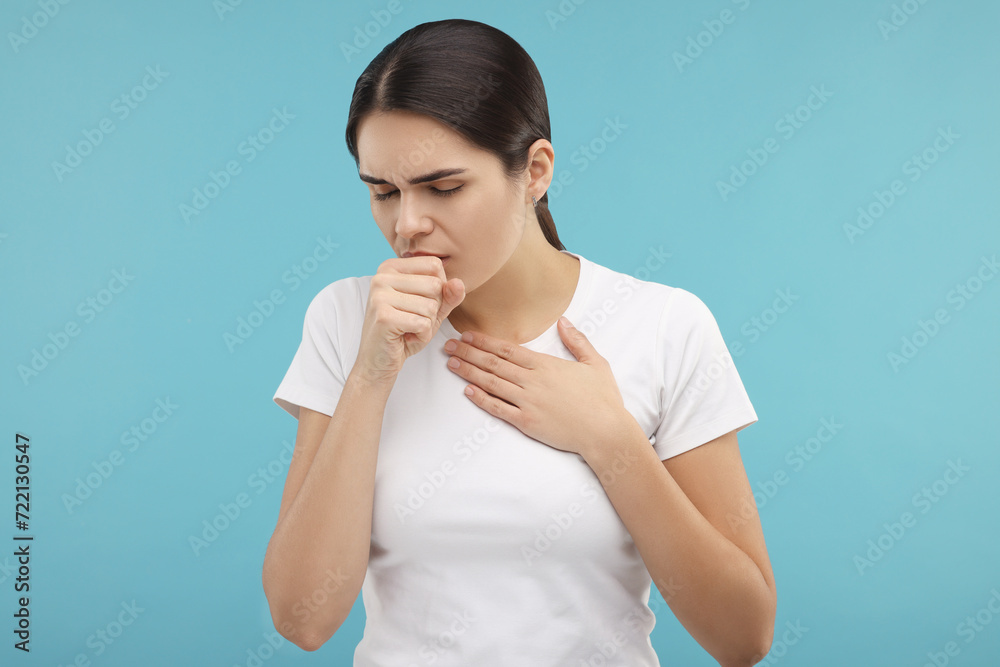 Woman coughing on light blue background. Cold symptoms Woman coughing on light blue background. Cold symptoms