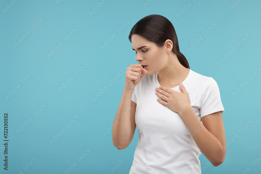 Woman coughing on light blue background, space for text. Cold symptoms