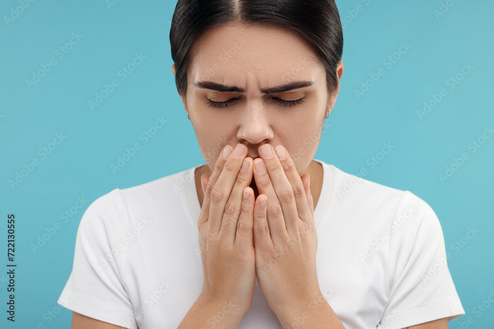 Woman coughing on light blue background. Cold symptoms Woman coughing on light blue background. Cold symptoms