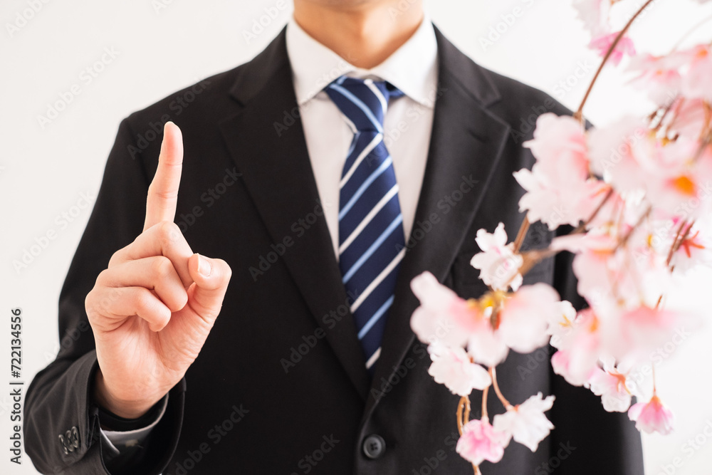 人差し指を立てるスーツの男性と桜