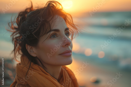 Serene contemplative woman in her forties enjoying a sunset on a pebble beach, with soft focus and warm tones. Created with Generative AI