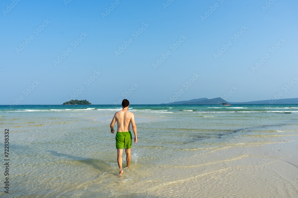 A person walking towards the sea on a sandy beach