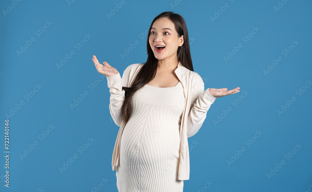 Portrait of pregnant asian woman, isolated on blue background