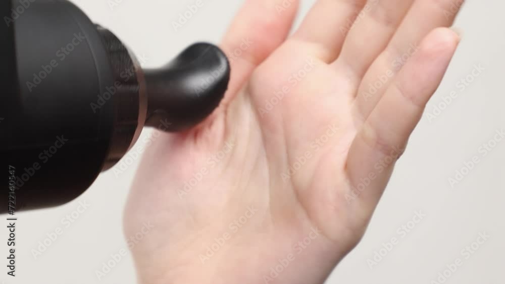 Close up of woman gives herself massage on palm with percussion massager-gun with finger nozzle. Therapy for joint pain relief. Close up of woman gives herself massage on palm with percussion massager-gun with finger nozzle. Therapy for joint pain relief.