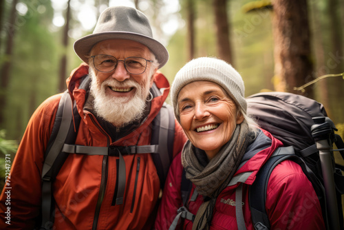 Senior couple hiking in the forest. They are looking at camera and smiling