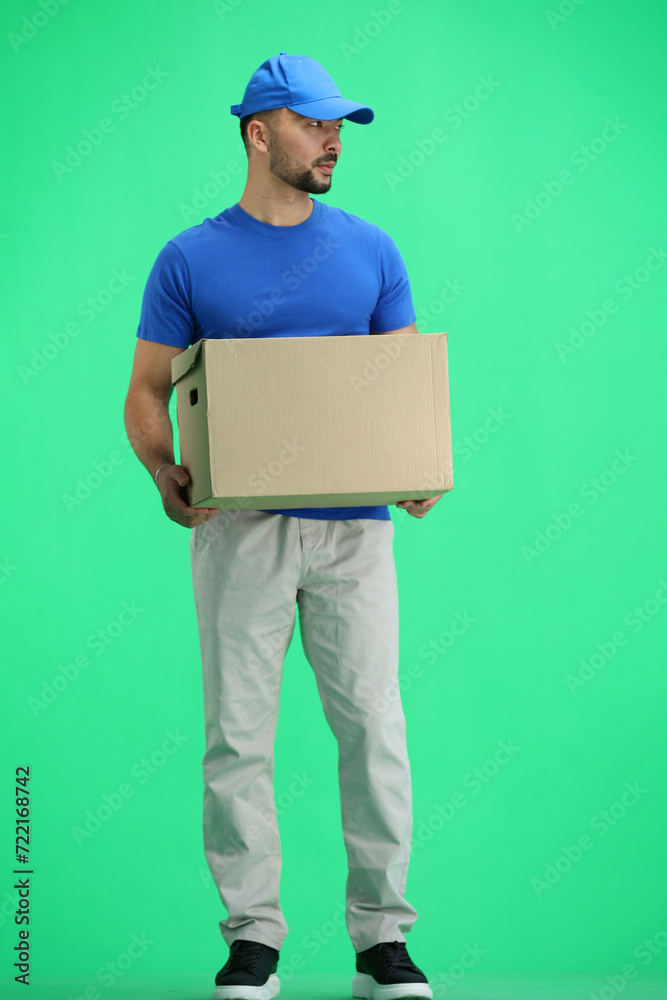 The deliveryman, full-length, on a green background, with a box The deliveryman, full-length, on a green background, with a box