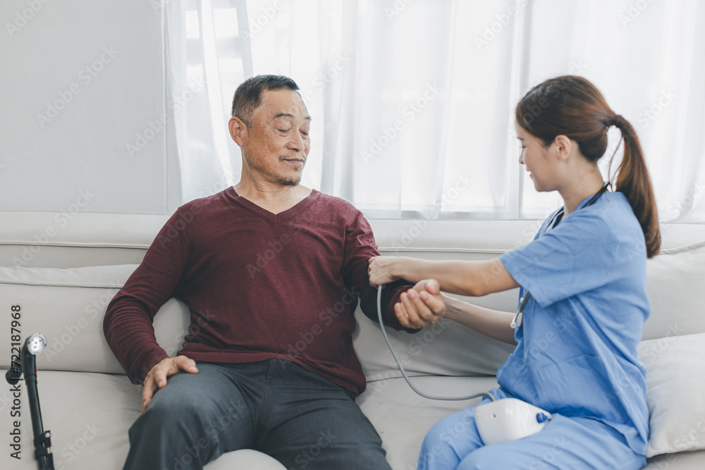 Obraz premium Caregiver nurse measuring blood pressure by using digital sphygmomanometer Senior patient at home. Caregiver nurse using medical device to measure blood pressure Senior patient