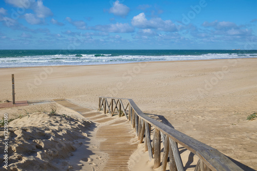 Wide sandy beach on the ocean. Wooden path leading to the beach.