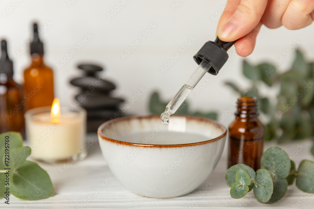 Eucalyptus essential oil in a glass bottle with green eucalyptus leaves on a textured wooden background. Aromatherapy concept. Spa. Natural organic ingredients for cosmetics and body care.Copy space