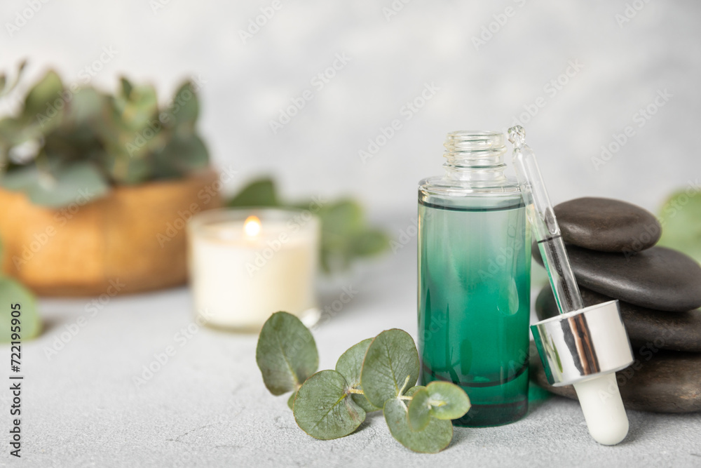 Eucalyptus essential oil in a glass bottle with green eucalyptus leaves on a textured wooden background. Aromatherapy concept. Spa. Natural organic ingredients for cosmetics and body care.Copy space