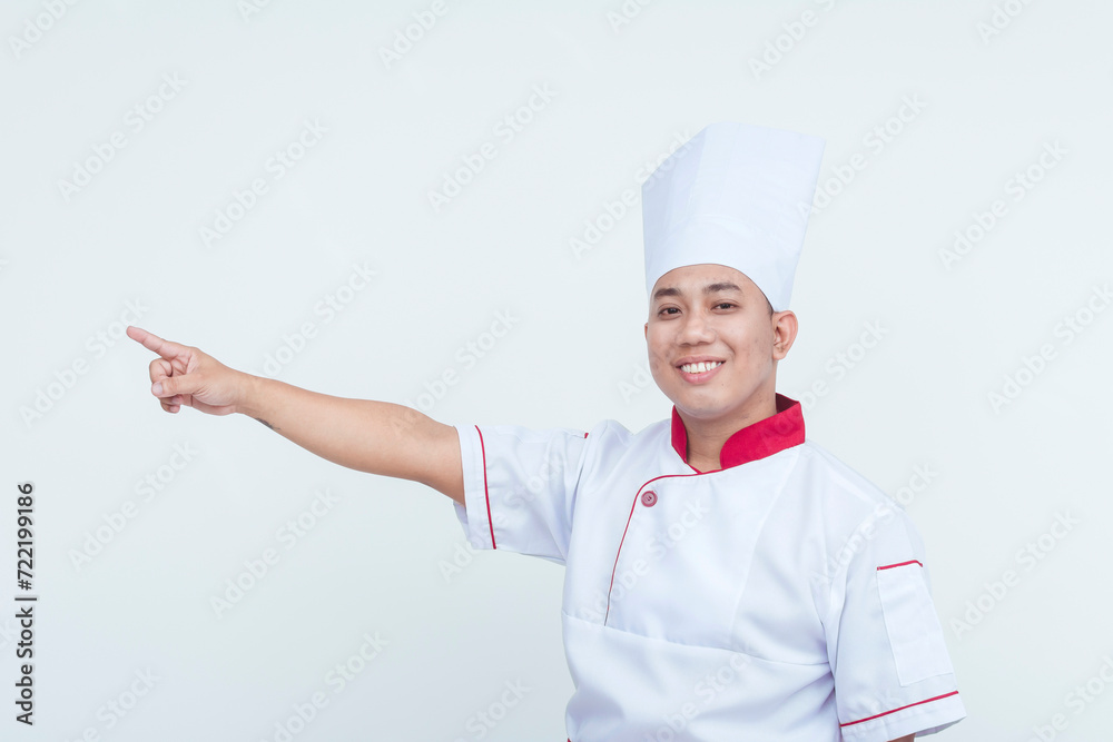 Happy Asian male chef in uniform pointing to the side, isolated on a white background, conveying a friendly gesture. Happy Asian male chef in uniform pointing to the side, isolated on a white background, conveying a friendly gesture.